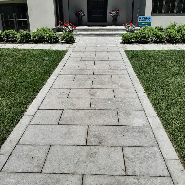 Application image for Limestone - Madison. The image shows this material being used for landscape curbing &amp; edging, path pavers and treads. The surface finish shown is flamed. The dominant color shown is gray; with beige, blue, purple, white and cream secondaries. The color mix creates a cool feeling. Regular and cloudy color patterns. Contains mineral inclusions.