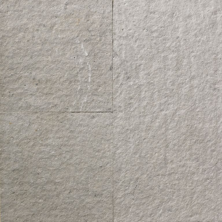 Feature image for Greyflek Limestone. The surface finish shown is flamed. The dominant color shown is gray; with beige, blue, brown, orange/rust, purple, tan and cream secondaries. The color mix creates a warm feeling. Regular color pattern. Contains mineral inclusions.