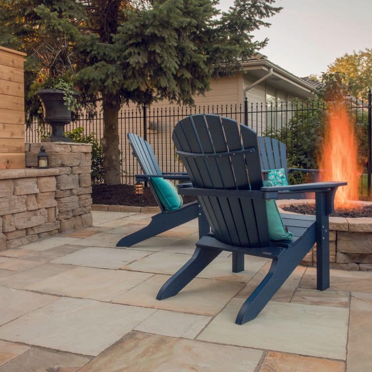 Application image for Golden Fossil Sandstone. The image shows this material being used in a patio pavers application. The surface finish shown is natural cleft. Dominant colors shown are brown and gray; with beige, blue, green, orange/rust, white and tan secondaries. Exhibits "movement". Regular and streaked color patterns.