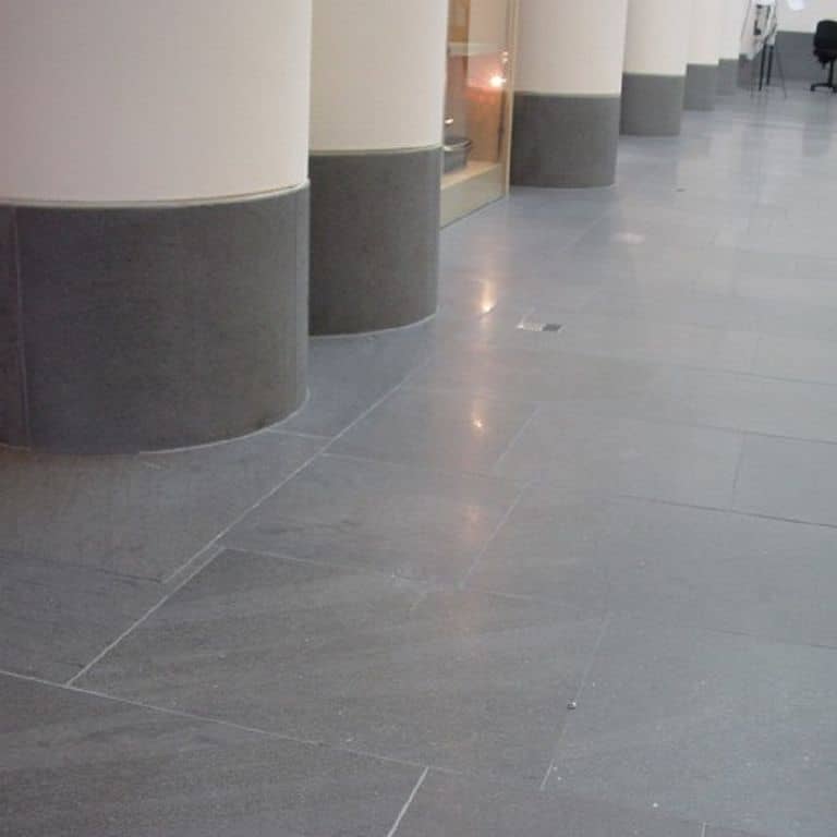 Application image for Basaltina Basalt. The image shows this material being used in an interior floor application. The surface finish shown is polished. The dominant color shown is gray. The color mix creates a warm feeling. Regular color pattern.