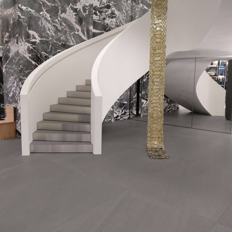 Application image for Basaltina Basalt. The image shows this material being used for interior floor and monolithic steps. The surface finish shown is brushed. The dominant color shown is gray. The color mix creates a warm feeling. Solid color pattern.