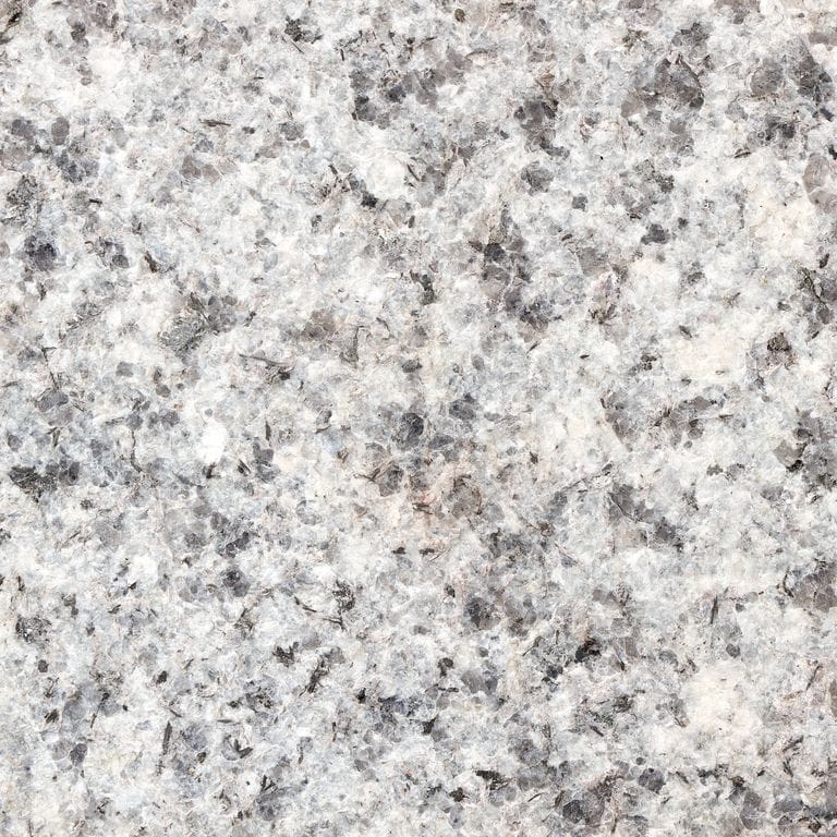 Feature image for Azul Platino Granite. The surface finish shown is flamed. The dominant color shown is gray; with beige, pink, purple, white and cream secondaries. The color mix creates a warm feeling. Coarse speckled color pattern. Contains some mica and mineral inclusions.