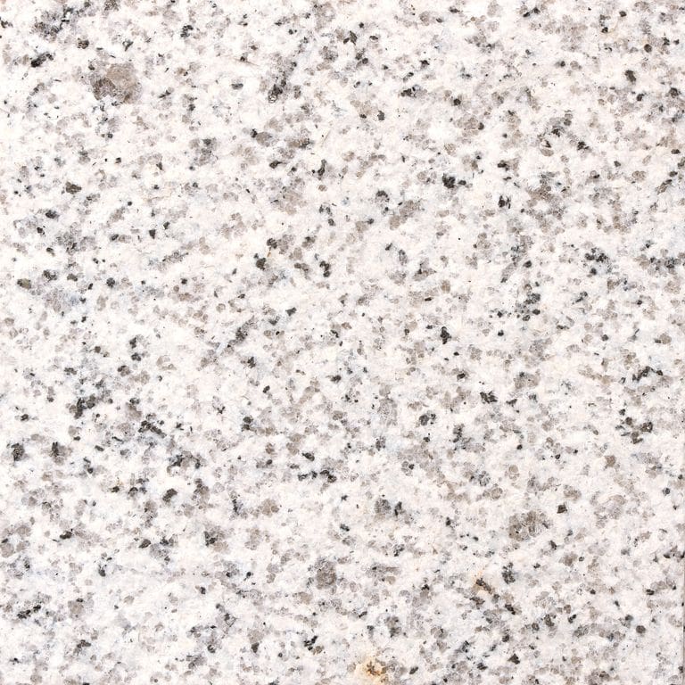 Feature image for Crystal White Granite. The surface finish shown is flamed. Dominant colors shown are gray, white and cream; with beige, pink and purple secondaries. The color mix creates a warm feeling. Fine speckled and coarse speckled color patterns. Contains some mica and mineral inclusions.