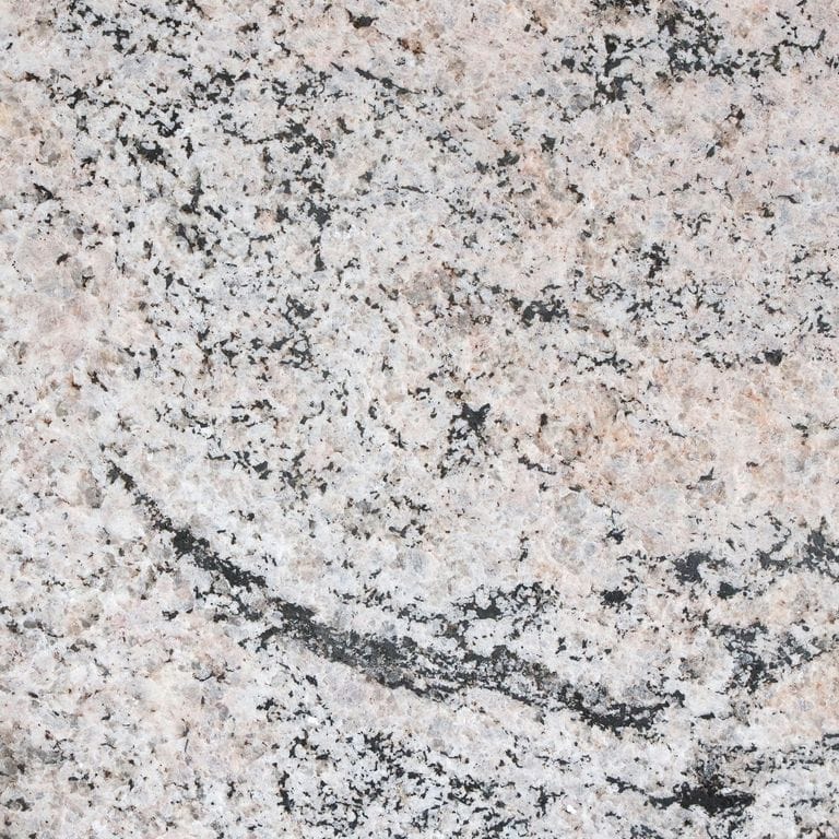 Best close-up image for Riverside Granite. The surface finish shown is flamed. The dominant color shown is gray; with beige, pink, purple, white and cream secondaries. Exhibits "movement" and the color mix creates a cool feeling. Fine speckled, swirled and random color patterns. Contains some mica and mineral inclusions.