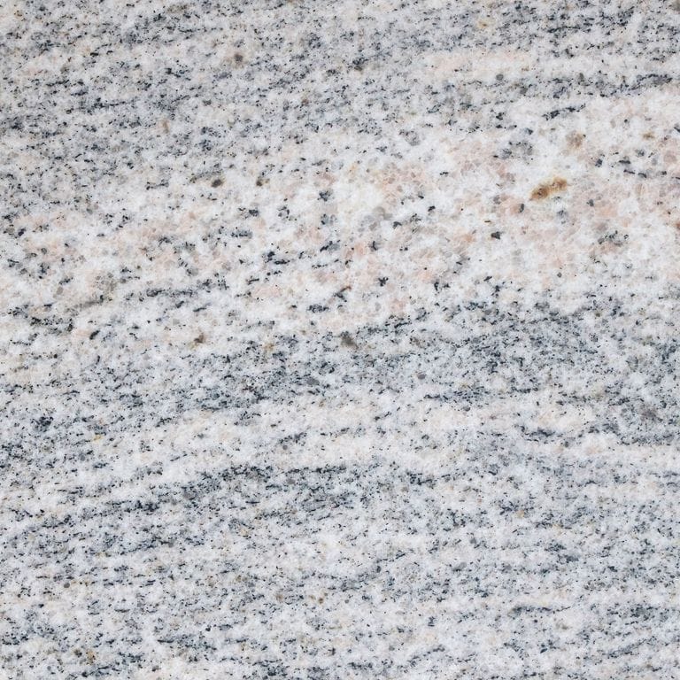 Feature image for Riverside Granite. The surface finish shown is honed. Dominant colors shown are gray and white; with beige, blue, pink and purple secondaries. Exhibits "movement" and the color mix creates a cool feeling. Linear, fine speckled and random color patterns.
