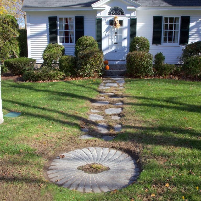 Feature image for Reclaimed Antique Farm and Mill Stones. The image shows this material being used for garden accents and path pavers. The surface finish shown is a combination of carved, weathered and worn. Dominant colors shown are gray and white; with beige and blue secondaries. The color mix creates a cool feeling. Regular color pattern.