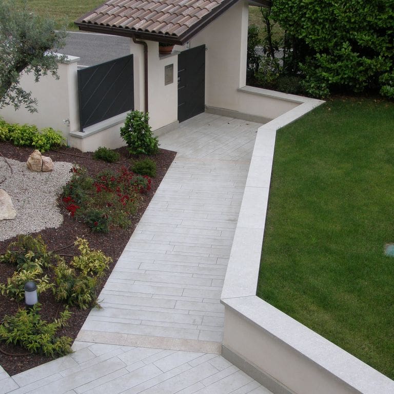 Application image for Veneto Olivo Limestone - Pavers. The image shows this product being used in a path pavers application. The surface finish shown is flamed. Dominant colors shown are beige, gray and tan. The color mix creates a warm feeling.