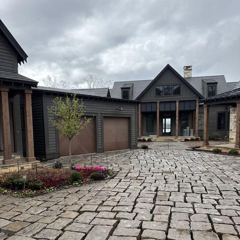 Application image for Reclaimed New England Granite - Bridge Squares. The image shows this product being used in a driveway pavers application. The surface finish shown is . The dominant color shown is gray. The color mix creates a warm feeling.