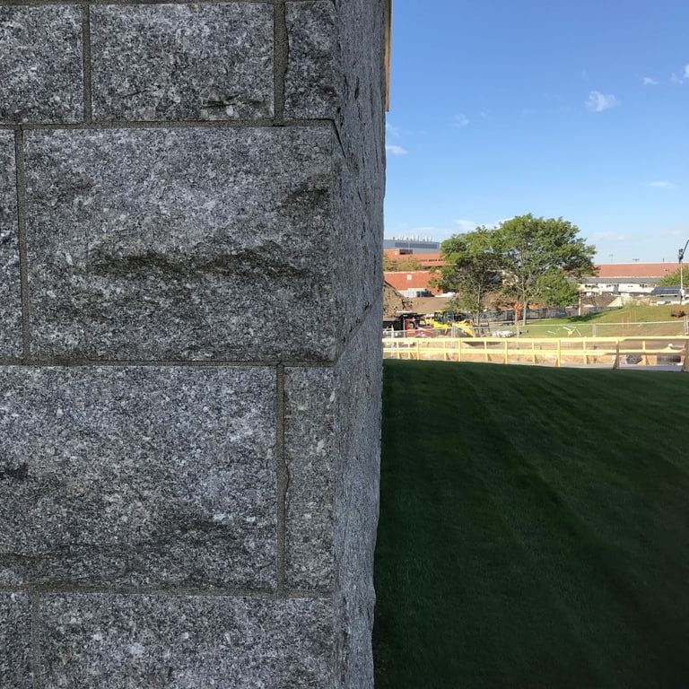 Best close-up image for Deer Isle Granite - Cut to Size Veneer. The image shows this product being used in a full bed veneer application. The surface finish shown is split-face. The dominant color shown is gray. The color mix creates a cool feeling.