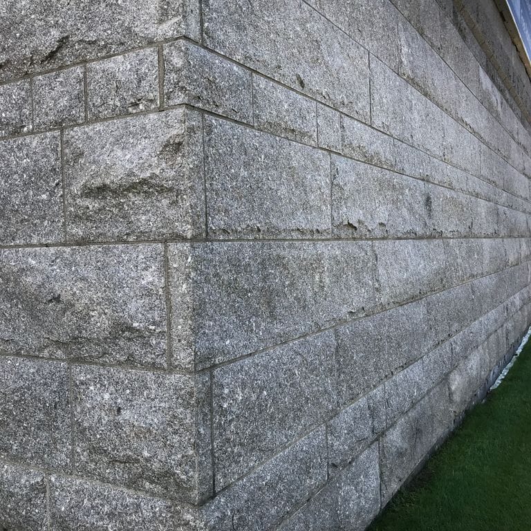 Feature image for Deer Isle Granite - Cut to Size Veneer. The image shows this product being used in a full bed veneer application. The surface finish shown is split-face. The dominant color shown is gray. The color mix creates a cool feeling.