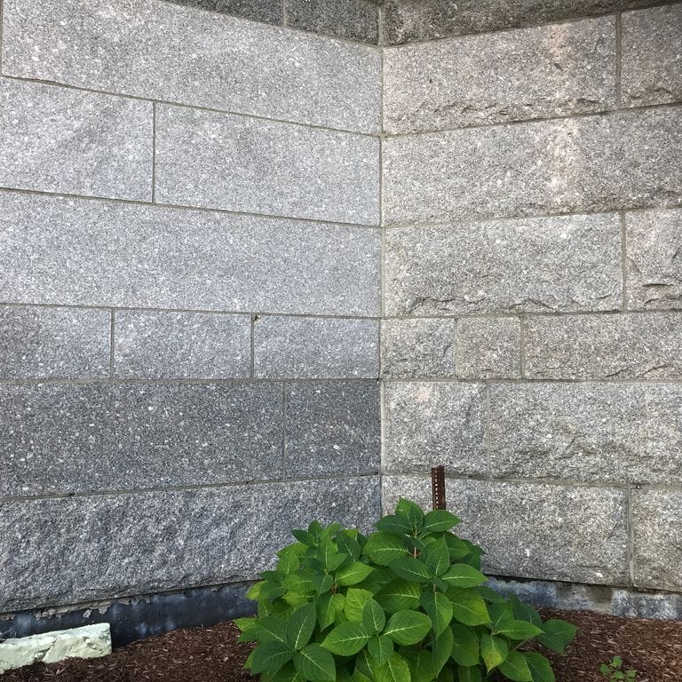 Application image for Deer Isle Granite - Cut to Size Veneer. The image shows this product being used in a full bed veneer application. The surface finish shown is split-face. The dominant color shown is gray. The color mix creates a cool feeling.