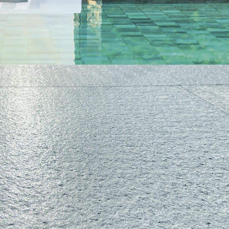 Best close-up image for Pietra Italia Gray Gneiss - Pool Deck. The image shows this product being used in a pool coping application. The dominant color shown is gray. The color mix creates a cool feeling.
