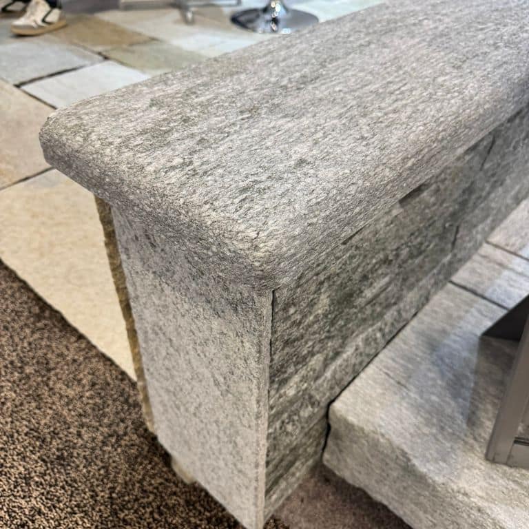 Application image for Pietra Italia Gneiss - Capstones. The image shows this product being used in a wallstone cap application. The surface finish shown is sand blasted. The dominant color shown is gray. The color mix creates a cool feeling.