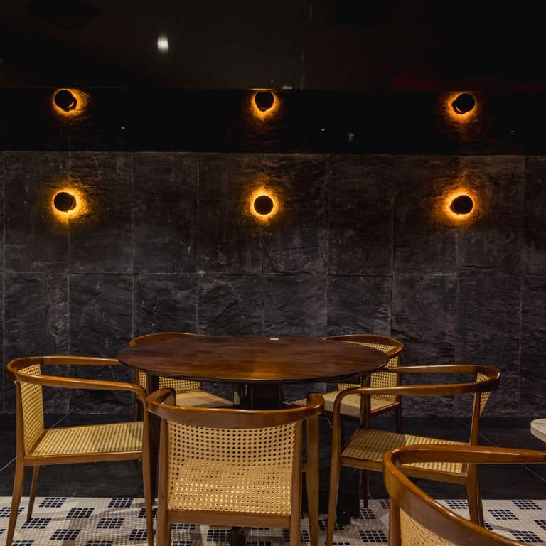 Feature image for Midnight Black Brazilian Gneiss - Cut to Size Veneer. The image shows this product being used in a full bed veneer application. The surface finish shown is split-face. The dominant color shown is black. The color mix creates a warm feeling.