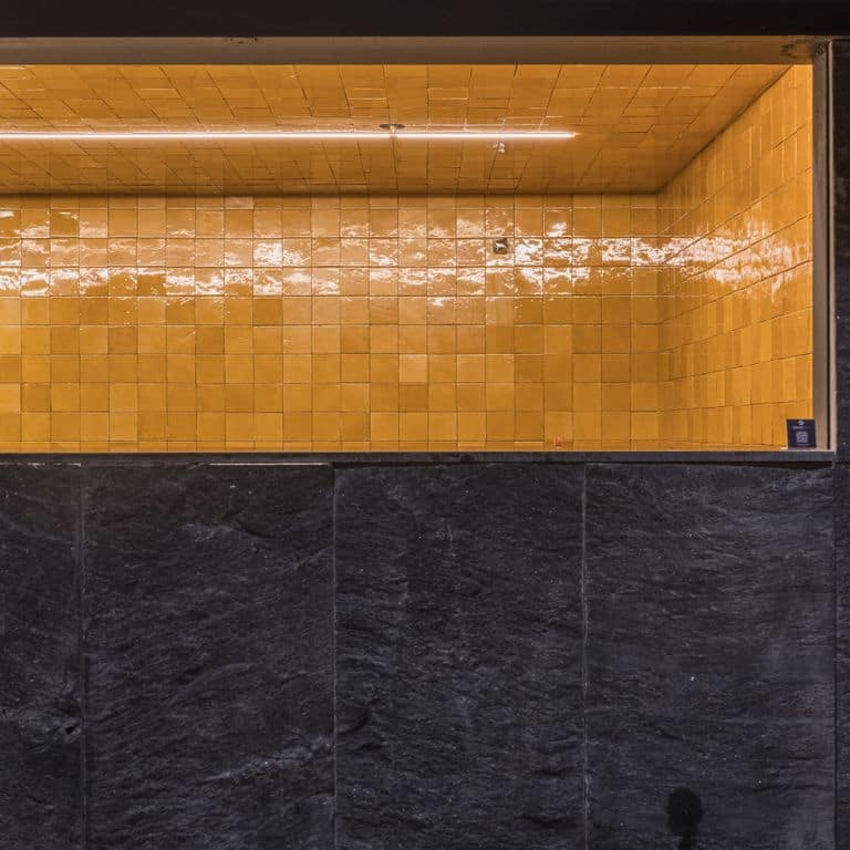Application image for Midnight Black Brazilian Gneiss - Cut to Size Veneer. The image shows this product being used in a full bed veneer application. The surface finish shown is split-face. The dominant color shown is black. The color mix creates a cool feeling.