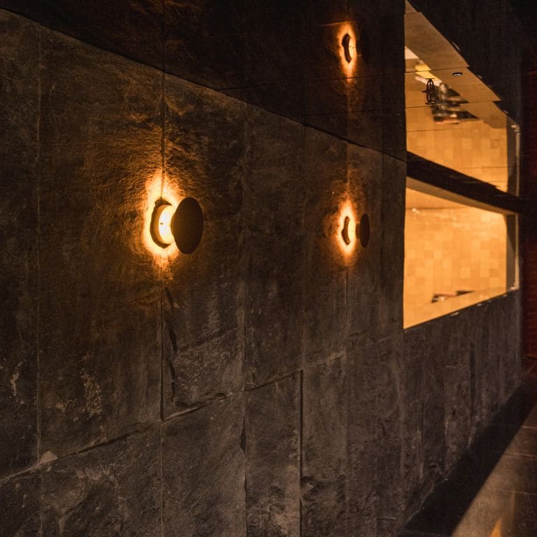 Application image for Midnight Black Brazilian Gneiss - Cut to Size Veneer. The image shows this product being used in a full bed veneer application. The surface finish shown is split-face. The dominant color shown is black. The color mix creates a warm feeling.
