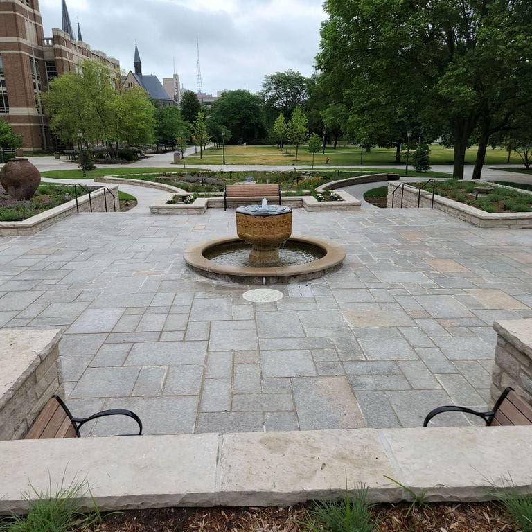 Application image for Madison Full Color Limestone - Pavers. The image shows this product being used in a patio pavers application. The surface finish shown is flamed. Dominant colors shown are gray and tan. The color mix creates a warm feeling. Regular color pattern.