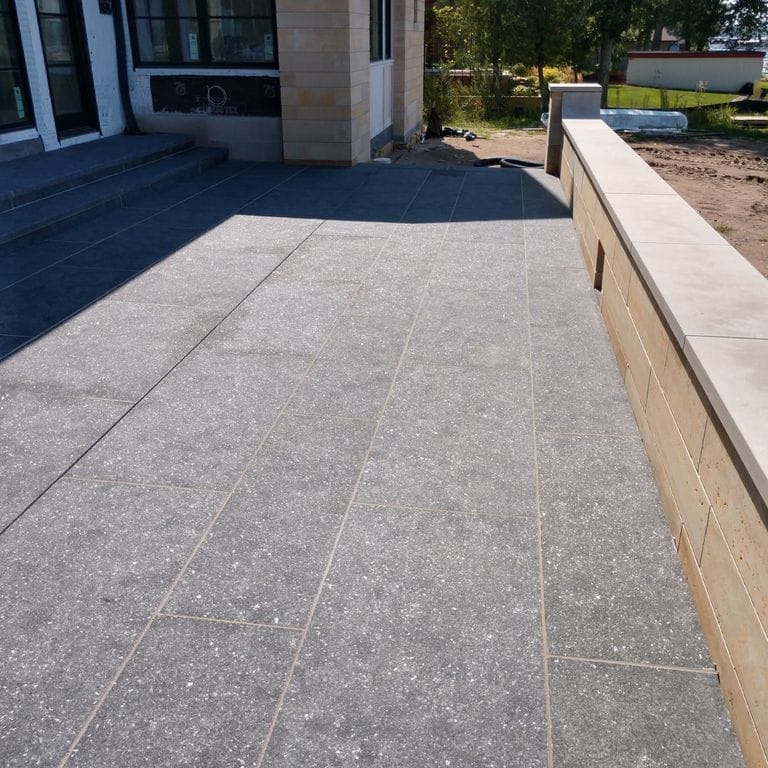 Best close-up image for Superior Northern Granite - Pavers. The image shows this product being used in a patio pavers application. Dominant colors shown are black and gray. The color mix creates a cool feeling.