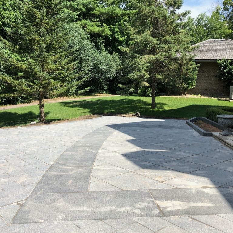 Application image for Superior Northern Granite - Pavers. The image shows this product being used in a patio pavers application. Dominant colors shown are black and gray.