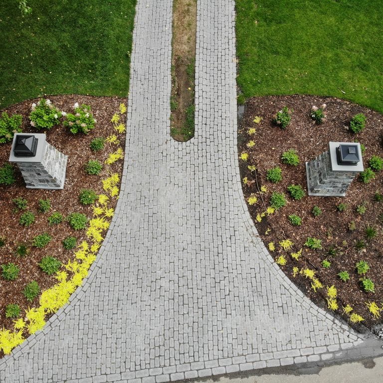 Application image for Superior Northern Granite - Cobblestones. The image shows this product being used for driveway pavers and driveway aprons. The surface finish shown is tumbled. Dominant colors shown are black and gray. The color mix creates a cool feeling.