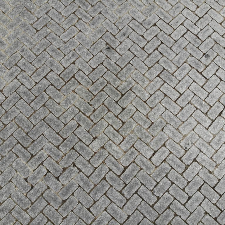 Application image for Superior Northern Granite - Cobblestones. The image shows this product being used in a driveway pavers application. The surface finish shown is tumbled. Dominant colors shown are black and gray.