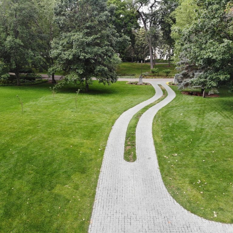 Application image for Superior Northern Granite - Cobblestones. The image shows this product being used for driveway pavers and driveway aprons. The surface finish shown is tumbled. Dominant colors shown are black and gray. The color mix creates a cool feeling.