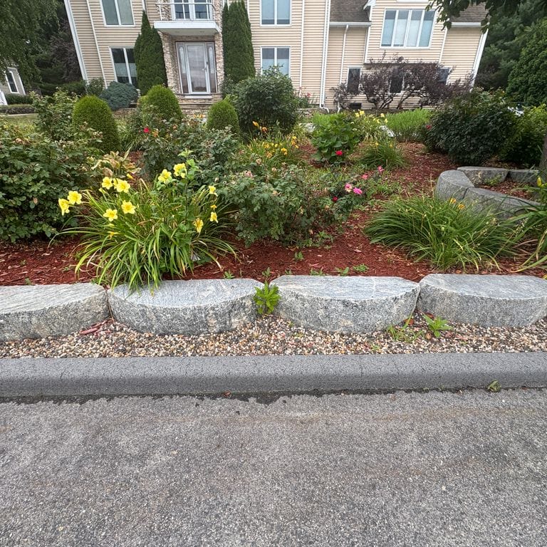 Application image for Reclaimed Granite D-Radius Curbstone - Edging. The image shows this product being used in a landscape curbing &amp; edging application. The dominant color shown is gray.