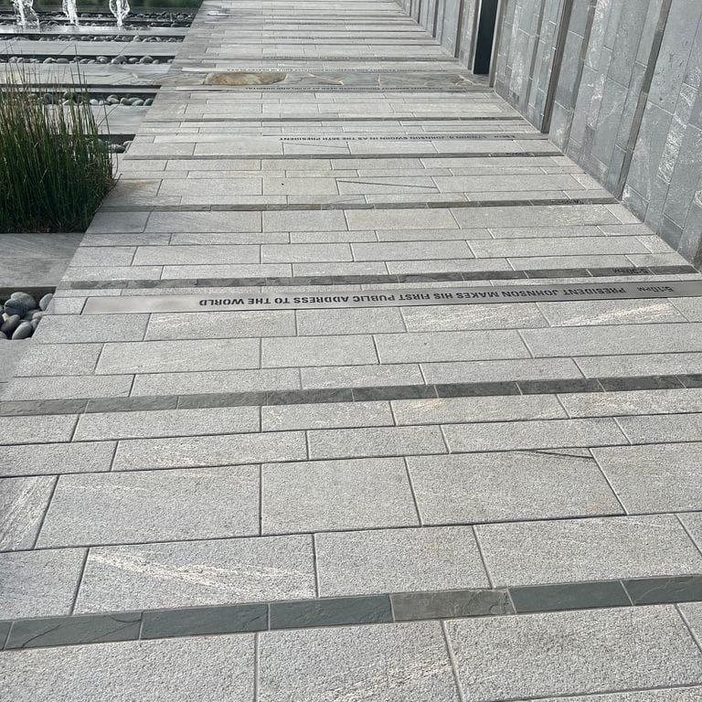 Feature image for Strata Mist Cross-Cut Gneiss - Pavers. The image shows this product being used for path pavers, patio pavers and public area. The dominant color shown is gray.