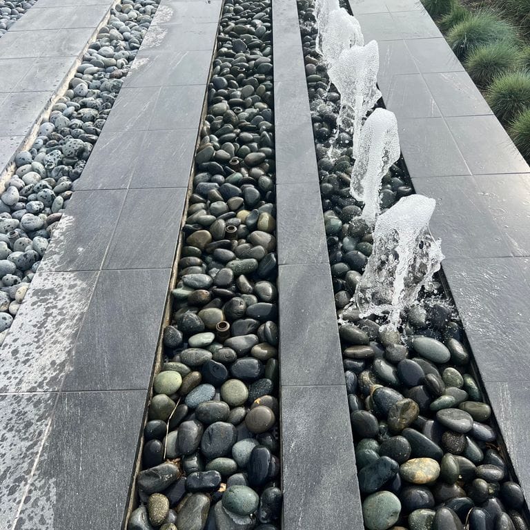 Application image for Strata Mist Cross-Cut Gneiss - Pavers. The image shows this product being used for water features and public area. The dominant color shown is gray. The color mix creates a cool feeling.