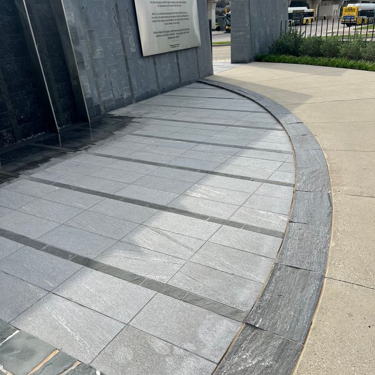 Application image for Strata Mist Cross-Cut Gneiss - Pavers. The image shows this product being used for patio pavers and public area. The dominant color shown is gray. The color mix creates a cool feeling.