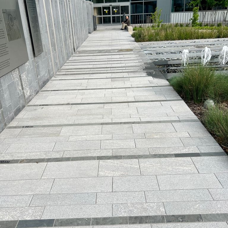 Application image for Strata Mist Cross-Cut Gneiss - Pavers. The image shows this product being used for patio pavers and public area. The dominant color shown is gray. The color mix creates a cool feeling.