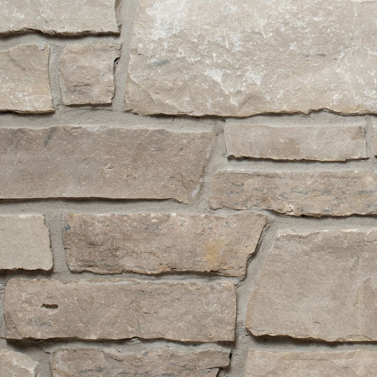 Feature image for Lannon Charcoal Limestone - Veneer. The image shows this product being used for full bed veneer and thin veneer. The surface finish shown is split-face. Dominant colors shown are gray and tan. The color mix creates a warm feeling.