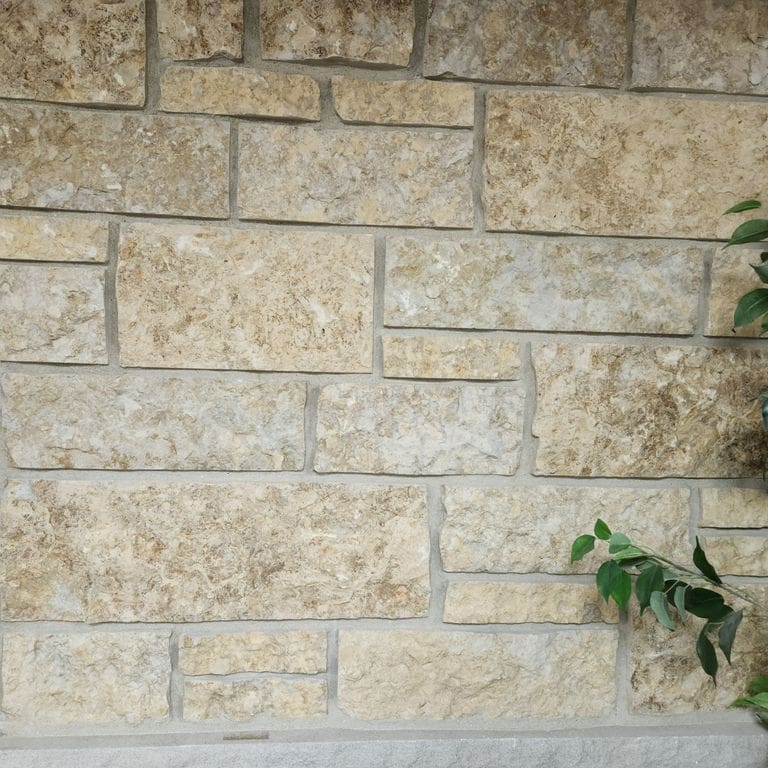 Application image for Golden Buff Limestone - Veneer. The image shows this product being used in a thin veneer application. The surface finish shown is split-face. Dominant colors shown are gray and tan. Exhibits "movement" and the color mix creates a warm feeling.