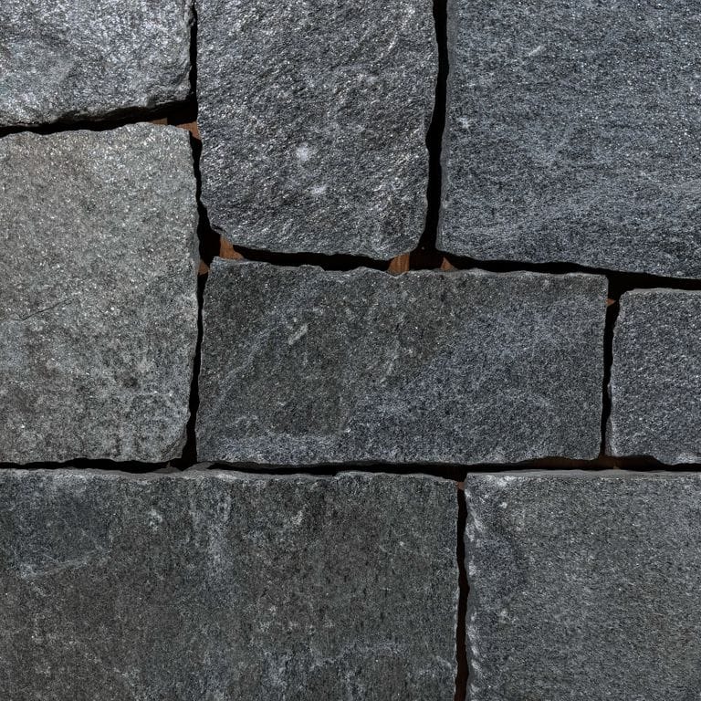 Color/Finish variation image for Old Chester Granite - Thin Veneer. The surface finish shown is split-face. Dominant colors shown are black and gray; with purple and white secondaries. The color mix creates a cool feeling. Regular, linear and streaked color patterns. Contains some mica and mineral inclusions.
