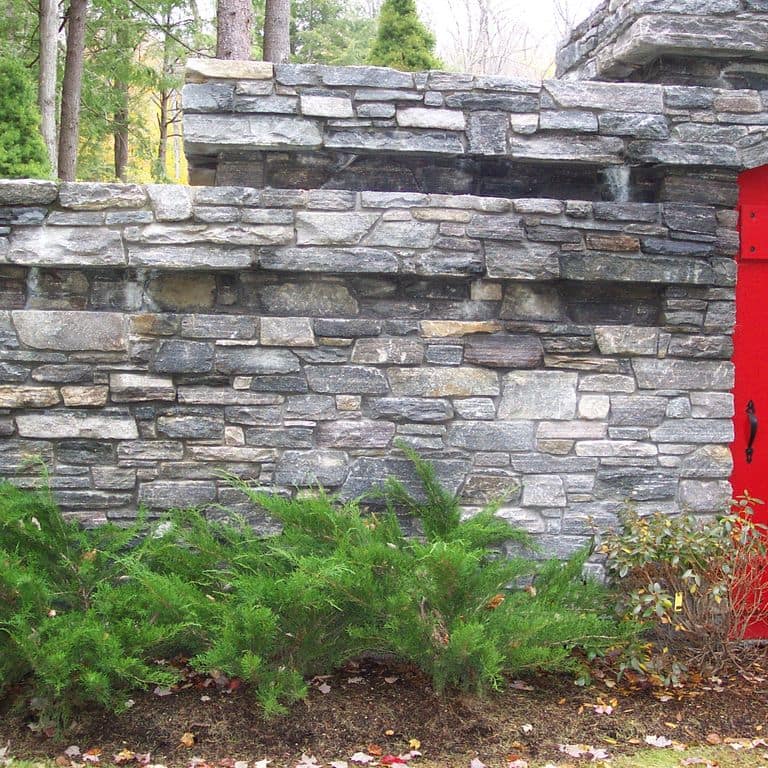 Application image for Chester Granite - Thin Veneer. The image shows this product being used for full bed veneer and thin veneer. The surface finish shown is split-face. The dominant color shown is gray; with beige, blue, purple, white and cream secondaries. The color mix creates a cool feeling. Streaked, speckled and random color patterns. Contains some mica and mineral inclusions.