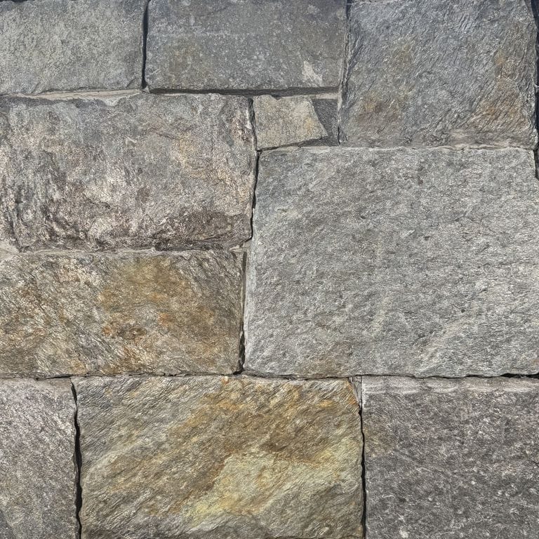 Feature image for Quimby Mountain Mica Granite - Thin Veneer. The surface finish shown is split-face. Dominant colors shown are gray and orange/rust. The color mix creates a warm feeling.