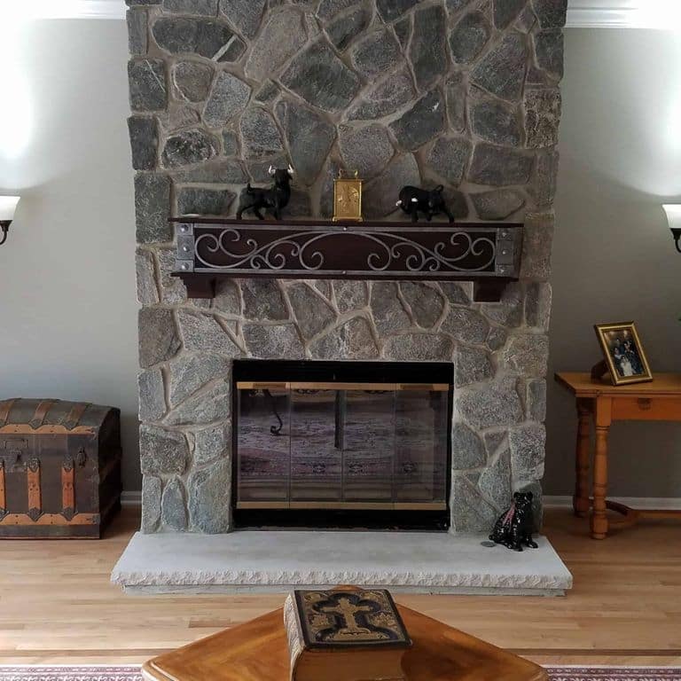 Application image for Oyster Bay Granite Thin Veneer - Mosaic. The image shows this product being used for fireplace surround and thin veneer. The dominant color shown is gray.