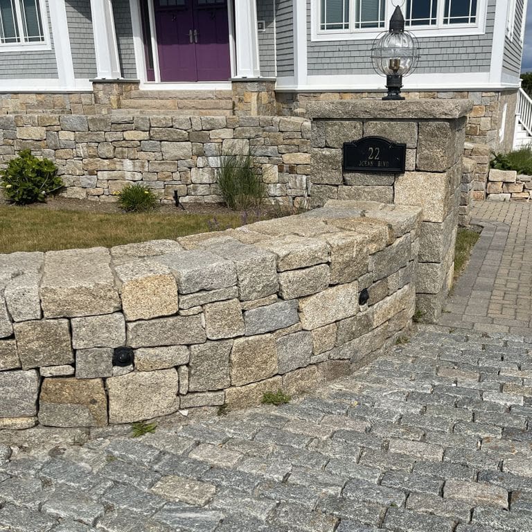 Application image for Cape Neddick Clear Granite - Wallstone. The image shows this product being used in a full bed veneer application. Dominant colors shown are beige, gray and tan. Speckled color pattern.