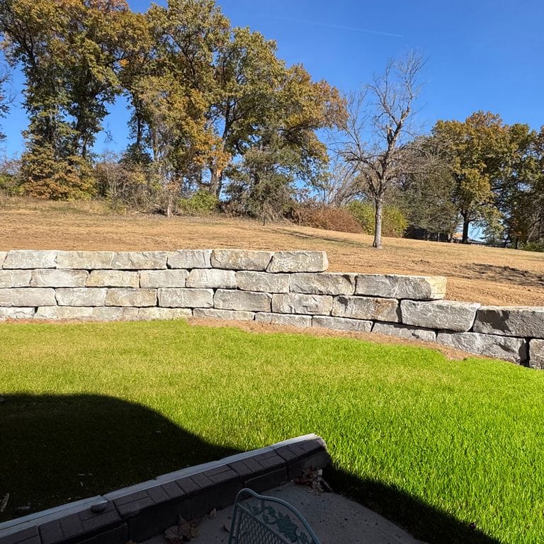 Feature image for Great Plains Limestone - Gray - Wallstone. The image shows this product being used for landscape wallstone and retaining wall. The surface finish shown is split-face. Dominant colors shown are gray and tan. The color mix creates a warm feeling.