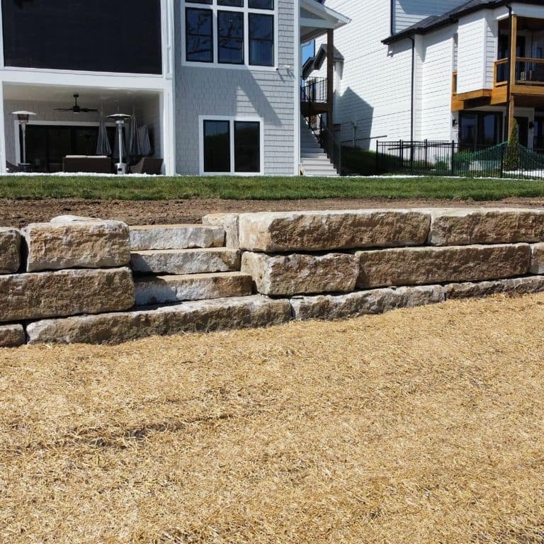 Feature image for Great Plains Limestone - Tan - Wallstone. The image shows this product being used for landscape wallstone and retaining wall. The surface finish shown is . Dominant colors shown are brown and tan. The color mix creates a warm feeling.