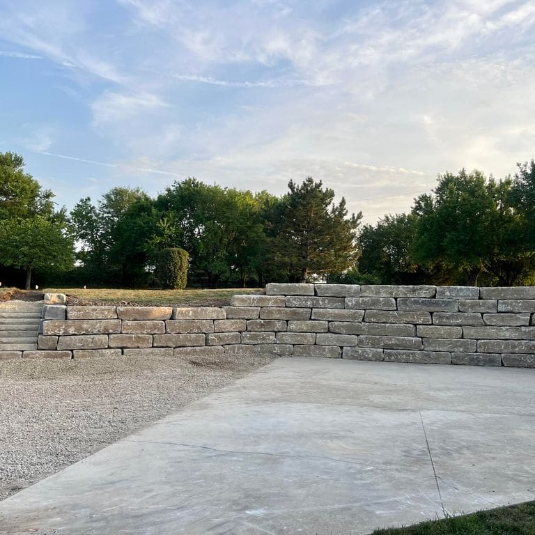 Application image for Great Plains Limestone - Tan - Wallstone. The image shows this product being used for landscape wallstone and retaining wall. The surface finish shown is . Dominant colors shown are gray and tan. The color mix creates a warm feeling.
