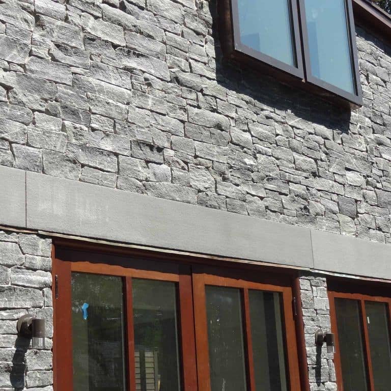 Application image for Greenwich Gray Granite Thin Veneer - Ashlar. The image shows this product being used in a thin veneer application. The surface finish shown is split-face. Dominant colors shown are black and gray. The color mix creates a cool feeling.