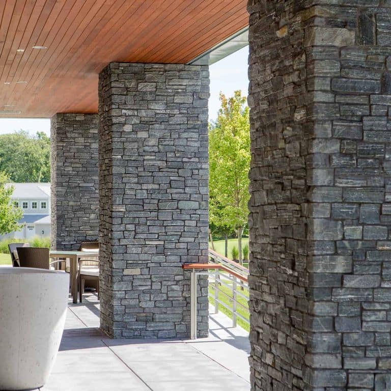 Feature image for Greenwich Gray Granite Veneer - Ledge. The image shows this product being used in a thin veneer application. The surface finish shown is split-face. Dominant colors shown are black and gray. The color mix creates a cool feeling.