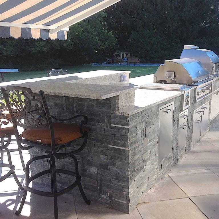 Application image for Greenwich Gray Granite Veneer - Ledge. The image shows this product being used in a thin veneer application. The surface finish shown is split-face. Dominant colors shown are black and gray. The color mix creates a cool feeling.