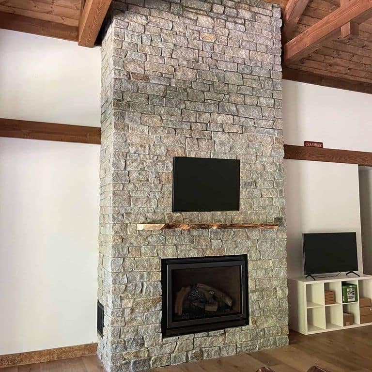 Feature image for Newport Mist Granite Veneer - Ledge. The image shows this product being used in a full bed veneer application. The surface finish shown is split-face. Dominant colors shown are gray and tan. The color mix creates a warm feeling.