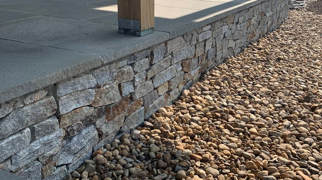 Application image for Newport Mist Granite Veneer - Ledge. The image shows this product being used in a full bed veneer application. The surface finish shown is split-face. Dominant colors shown are gray and tan. The color mix creates a warm feeling.