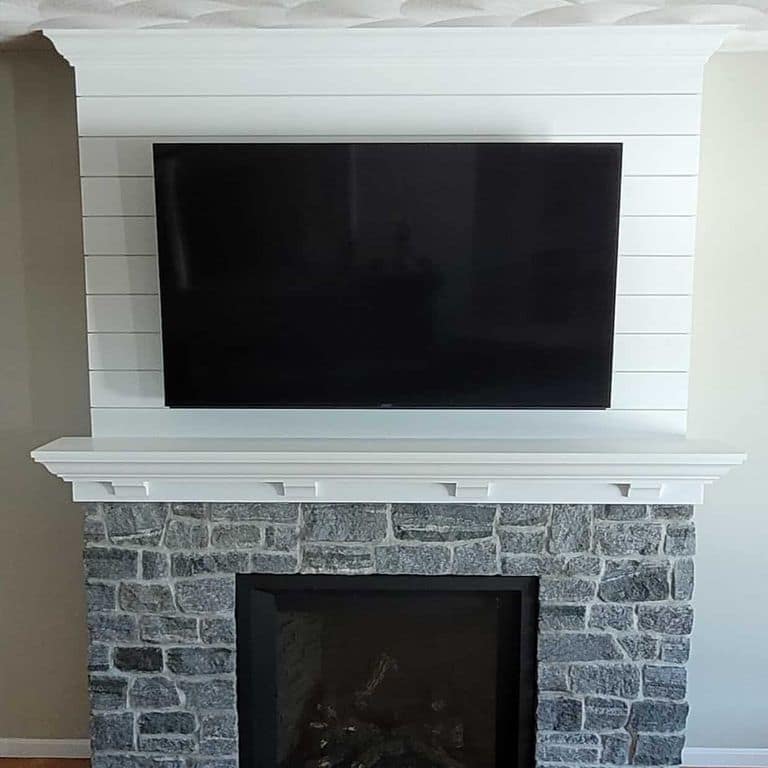 Application image for Oyster Bay Granite Thin Veneer - Ashlar. The image shows this product being used for fireplace surround and thin veneer. The surface finish shown is split-face. The dominant color shown is gray. The color mix creates a cool feeling.