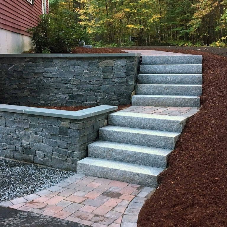 Application image for Oyster Bay Granite Thin Veneer - Ledge. The image shows this product being used in a thin veneer application. The surface finish shown is split-face. The dominant color shown is gray. The color mix creates a cool feeling.