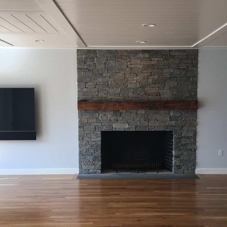 Application image for Oyster Bay Granite Thin Veneer - Ledge. The image shows this product being used for fireplace surround and thin veneer. The surface finish shown is split-face. The dominant color shown is gray. The color mix creates a cool feeling.