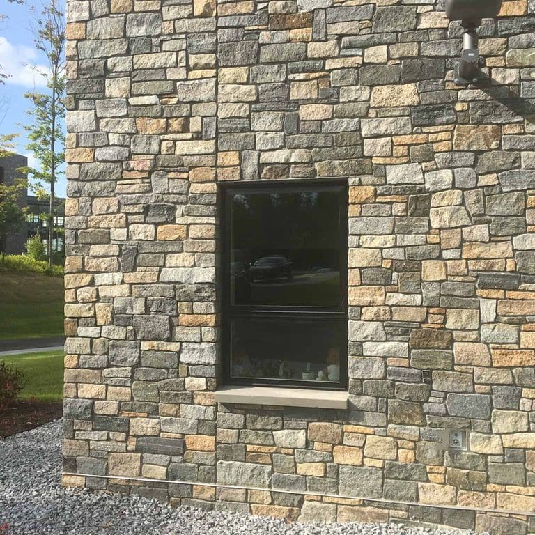 Application image for Boston Blend Granite Thin Veneer - Ashlar. The image shows this product being used in a full bed veneer application. The surface finish shown is split-face. Dominant colors shown are gray and tan. The color mix creates a warm feeling.